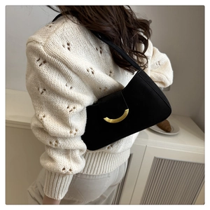 Side view of a vintage black suede shoulder bag with a gold crescent buckle on a model