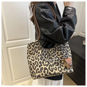 Detail view of large leopard print tote bag with brown leather strap and white script text