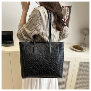 Sac fourre-tout noir tissé porté à l'épaule pour montrer le style et les dimensions