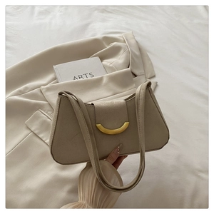 Detailed shot of beige suede hobo bag with a gold crescent buckle on elegant fabric