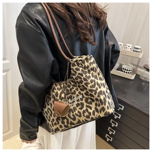Detail of leopard print tote bag featuring brown leather straps and small coin purse attachment