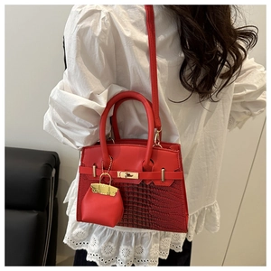 Detail of red croc-embossed leather handbag with metallic turn-lock and mini charm
