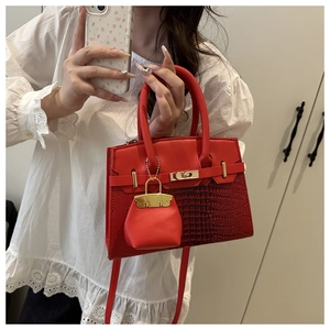 Detail of red crocodile pattern leather handbag with metal turn lock and sub-bag