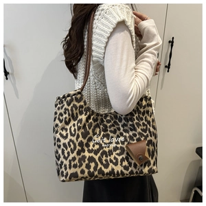 Detail of leopard print tote bag with brown leather straps and mini pouch accessory