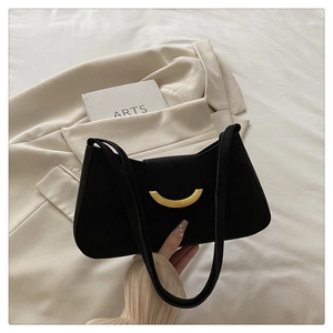 Detail of black underarm bag featuring a crescent gold metal buckle and matte leather texture