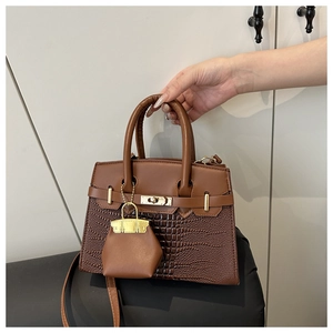 Detail of crocodile pattern leather handbag with gold twist lock and mini charm