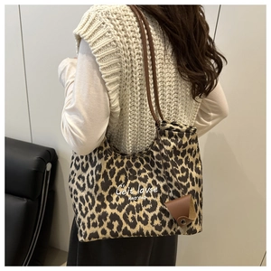 Detail of leopard print tote bag with brown straps and small leather pouch accessory