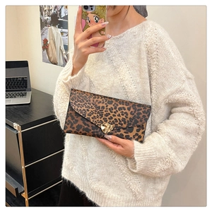 Detail of leopard print envelope clutch featuring a gold geometric metal buckle closure