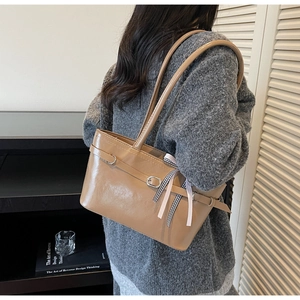 Détail du sac à épaule en cuir marron clair avec boucle et ruban de soie rayé décoratif