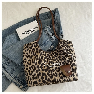 Detail of leopard print tote bag with brown leather straps and mini pouch accessory