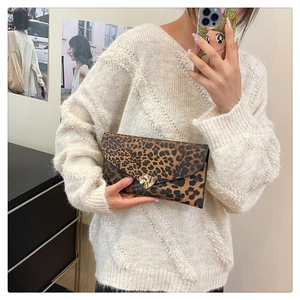Detail of leopard print envelope clutch featuring a gold triangular metal buckle closure