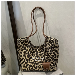 Detail of leopard print suede tote bag with brown leather handles and brand embroidery