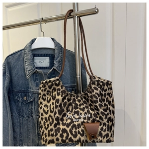 Detail view of leopard print tote bag with white script text and brown hanging charm