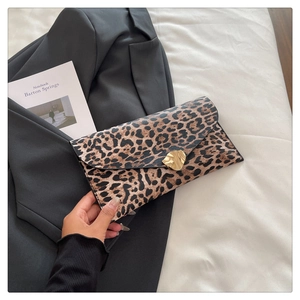 Close-up of leopard print clutch bag with an elegant gold buckle on black suit background