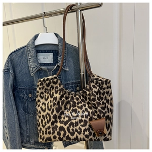 Close-up of leopard print suede tote bag with brown straps and leather triangle charm