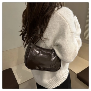 Detail view of glossy brown leather shoulder bag with embossed heart and letter M logo