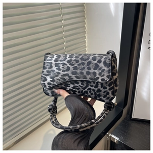 Detail shot of the knotted strap and grey leopard print texture on a shoulder bag