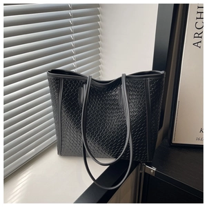 Close-up of black woven leather texture and shoulder straps on a minimalist tote bag