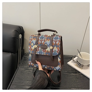 Close-up of geometric woven multi-color backpack with brown leather trim and metal logo