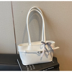 Détail d'un cabas en cuir PU blanc avec boucle et pendentif nœud à carreaux sur livres