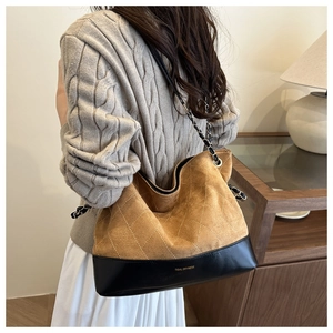 Detail of quilted brown suede and black leather patchwork tote with metal chain strap