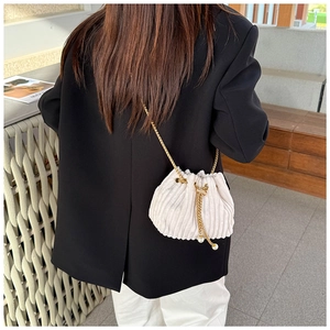 Detailed view of white corduroy bucket bag with gold chain and pearl drawstring charms