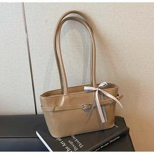 Détail du sac cabas en cuir café avec boucle métallique et ruban à carreaux décoratif