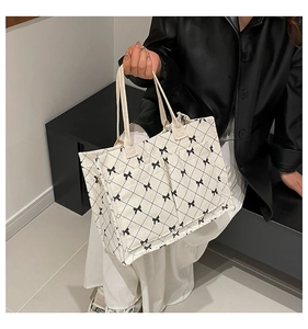 Detailed view of white canvas tote bag with black quilted pattern and bow accents