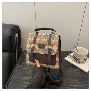Detailed view of vintage plaid backpack with brown leather trim on a wooden table