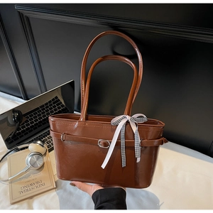 Vue détaillée d'un sac cabas marron avec ruban et ordinateur dans un décor lifestyle