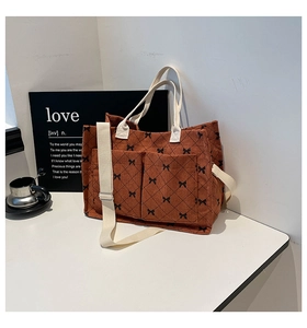 Detail of corduroy tote bag with bow pattern, showing dual front pockets and white strap