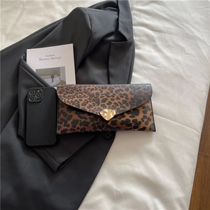 Leopard print envelope clutch bag with heart gold buckle on a stylish suit backdrop