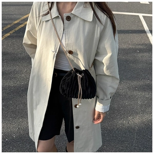Detail of black corduroy bucket bag featuring gold chain and elegant pearl drawstrings