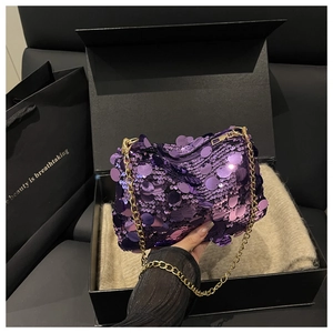Detail of purple sequin crossbody bag with gold chain strap in a black gift box