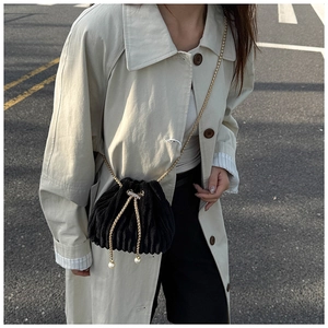 Detail of black corduroy bucket bag with pearl drawstring and golden chain strap