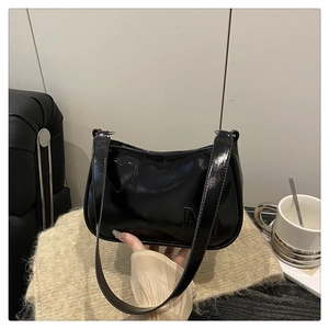 Detail of black patent leather shoulder bag with heart patch and M letter decoration