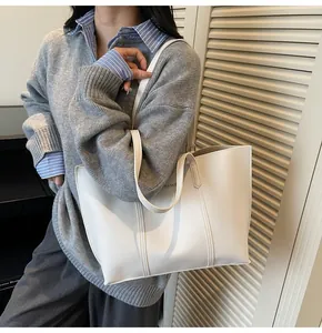 White leather tote bag with FASHION & BAGS lettering shown in a stylish commute setting