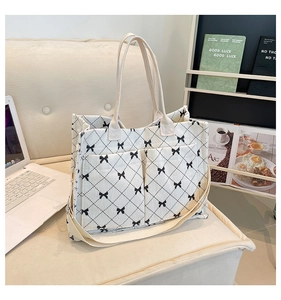 Detail of corduroy quilted tote bag with black bow print and adjustable strap