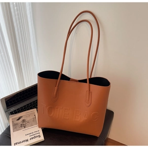 Detail of caramel orange tote bag with embossed lettering in a modern office setting