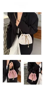 Detail of corduroy bucket bag featuring gold metal chain and white pearl drawstring charms