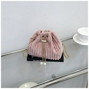 Detailed texture of pink corduroy bucket bag with gold chain and pearl drawstring charms