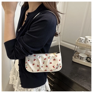 Detail of white cherry print underarm bag featuring trendy pleated design and gold zipper