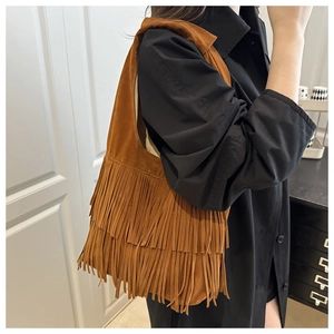 Dettaglio di una borsa tote in pelle scamosciata marrone con frange e tracolla larga