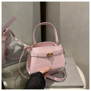 Detail of pink crocodile pattern bag showing golden metal clasp and logo print