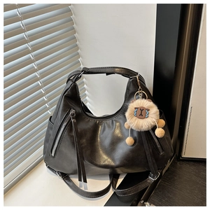 Detail of black hobo bag with silver zippers, tassels and cute plush sheep charm