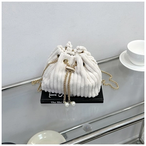 Detail of white corduroy bucket bag with drawstring closure and elegant pearl accents