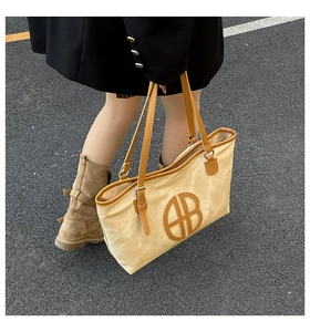 Detail of canvas tote bag showing textured beige fabric and adjustable brown leather strap