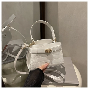 Detailed view of white crocodile pattern crossbody bag with golden twist lock and top handle