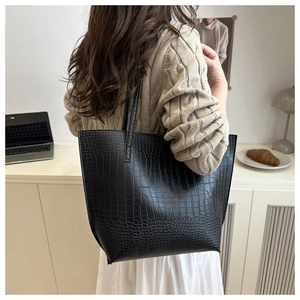 Detail of black crocodile embossed tote bag on model, showcasing textured faux leather surface