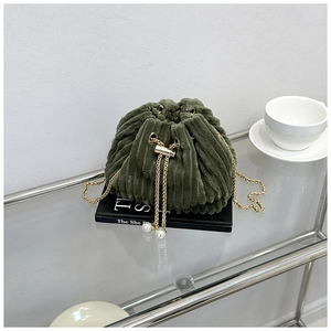 Detail of green corduroy drawstring bucket bag with gold chain and pearl accents